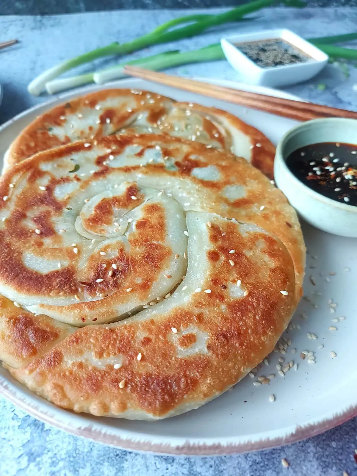 Close up shot of crispy savory pancakes with a soy sauce dipping sauce on the side