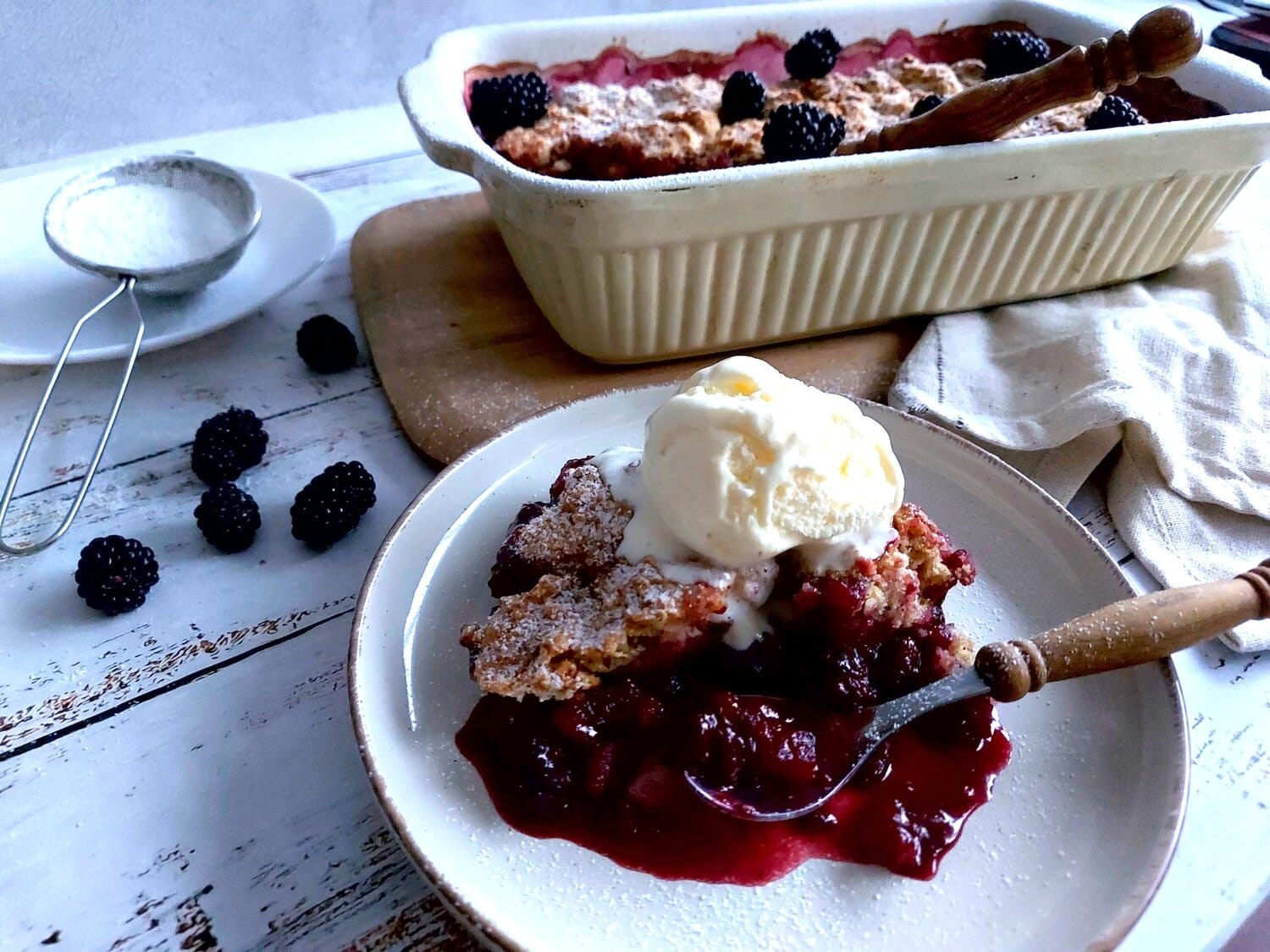 Fresh Blackberry Cobbler on a plate next to the baking tray