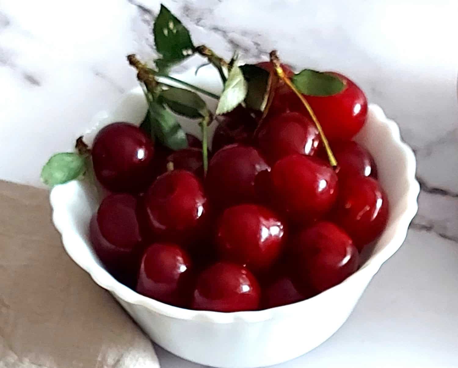 fresh sour cherries in a white bowl