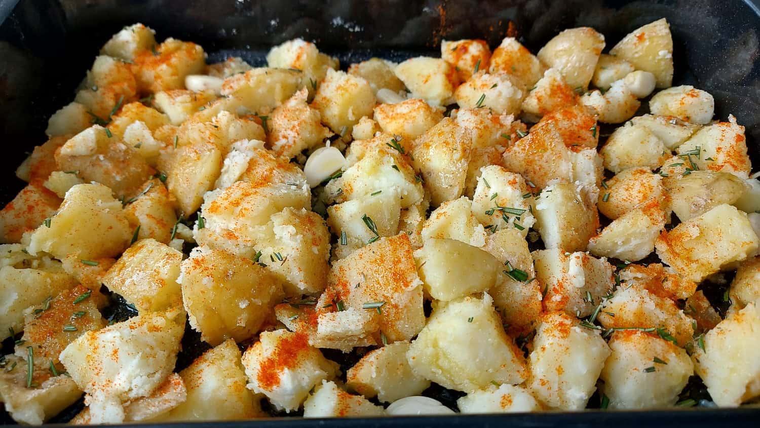 PARBOILED POTATOES WITH ROSEMARY, PAPRIKA AND GARLIC IN A TRAY