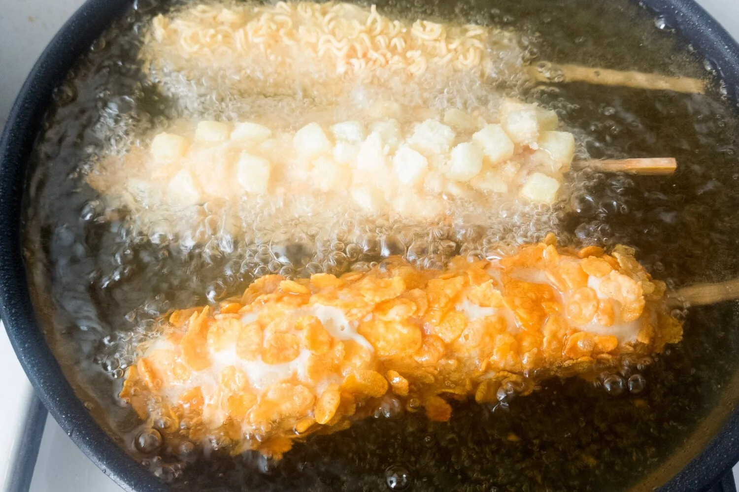 CHEESE CORN DOGS FRYING IN A SAUCEPAN