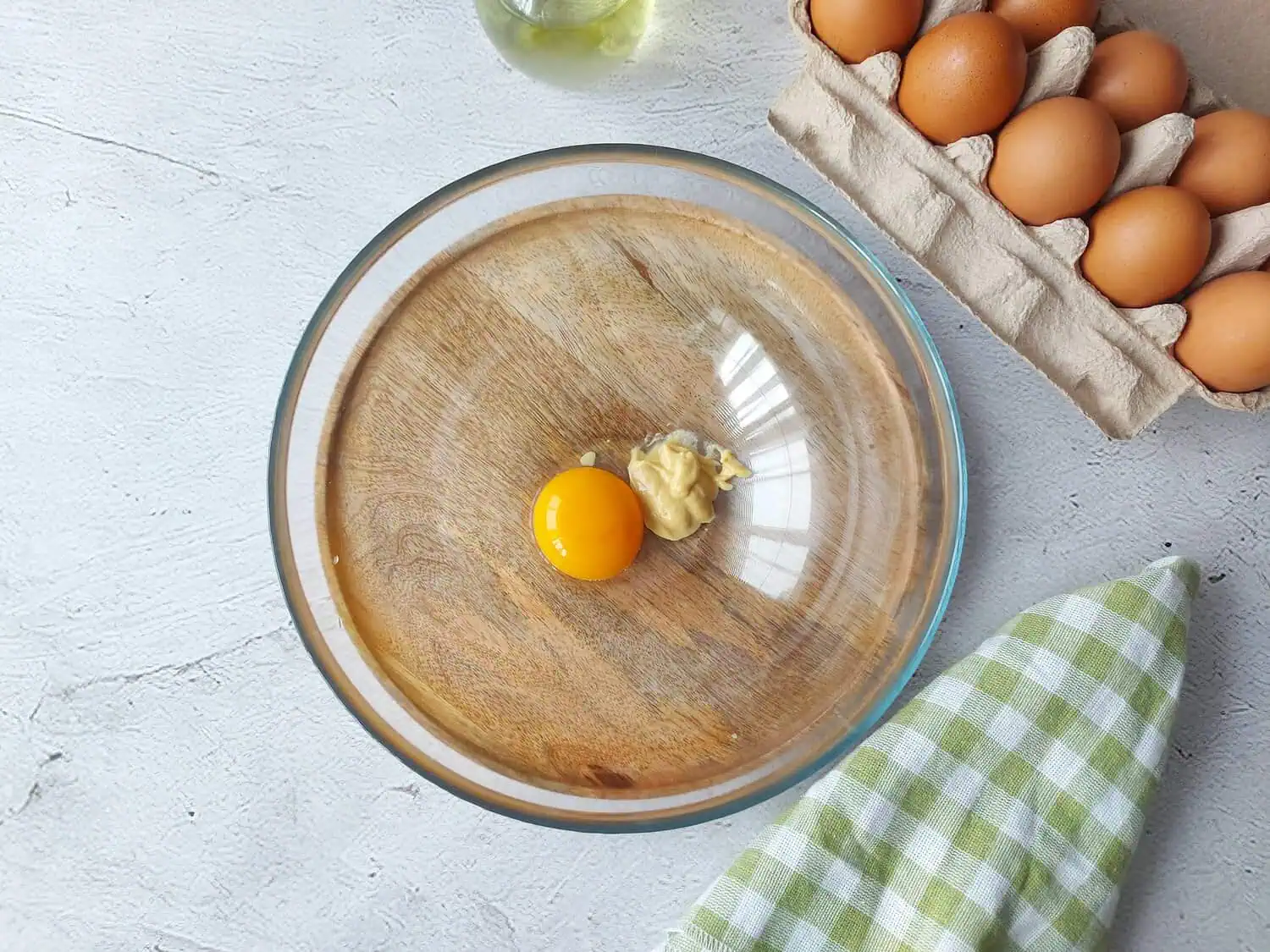 Egg yolk, mustard, and lemon juice in a glass bowl for making mayonnaise 