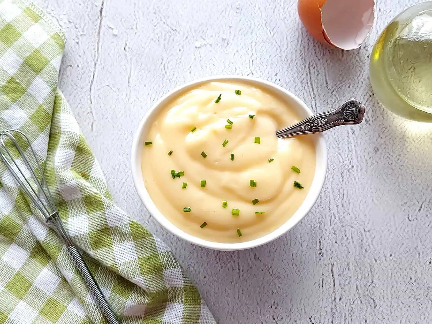 Close up of a small white bowl with traditional mayonnaise, and a spoon