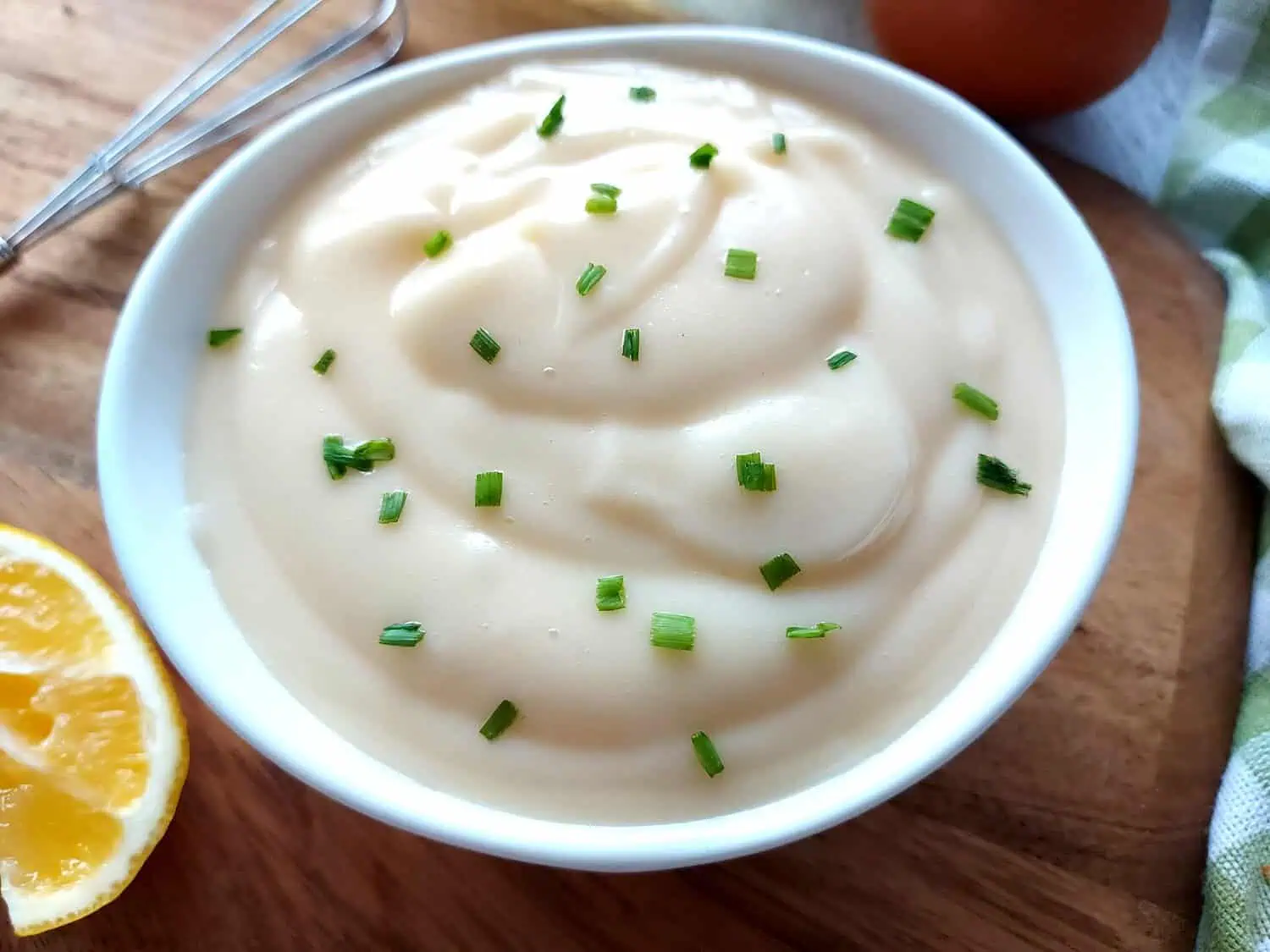 Homemade mayonnaise bowl with chives on a wooden board