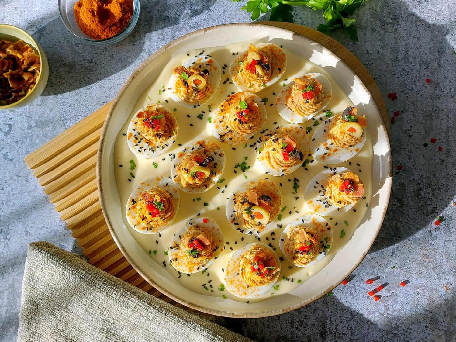 OVERHEAD SHOT OF A PLATTER WITH STUFFED EGGS IN MAYONNAISE ON A WOODEN BOARD AND A NAPKIN