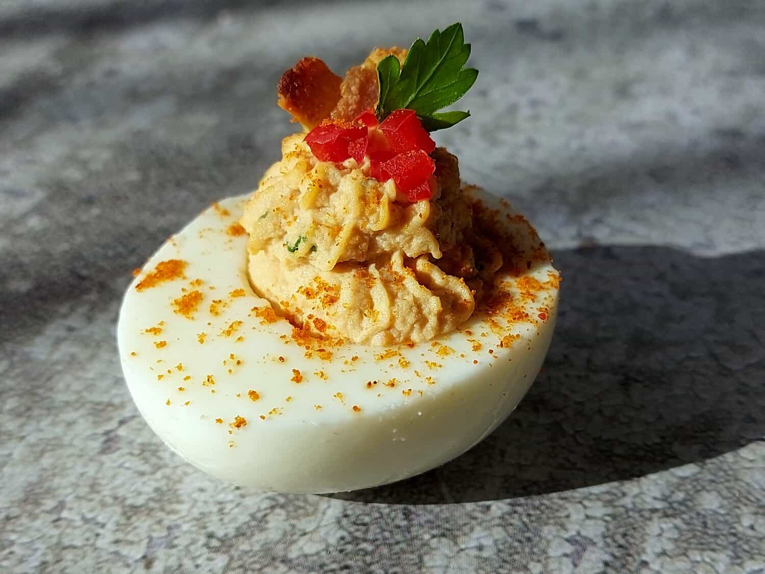 ONE DEVILED EGG ON A A GREY SLATE BACKGROUND