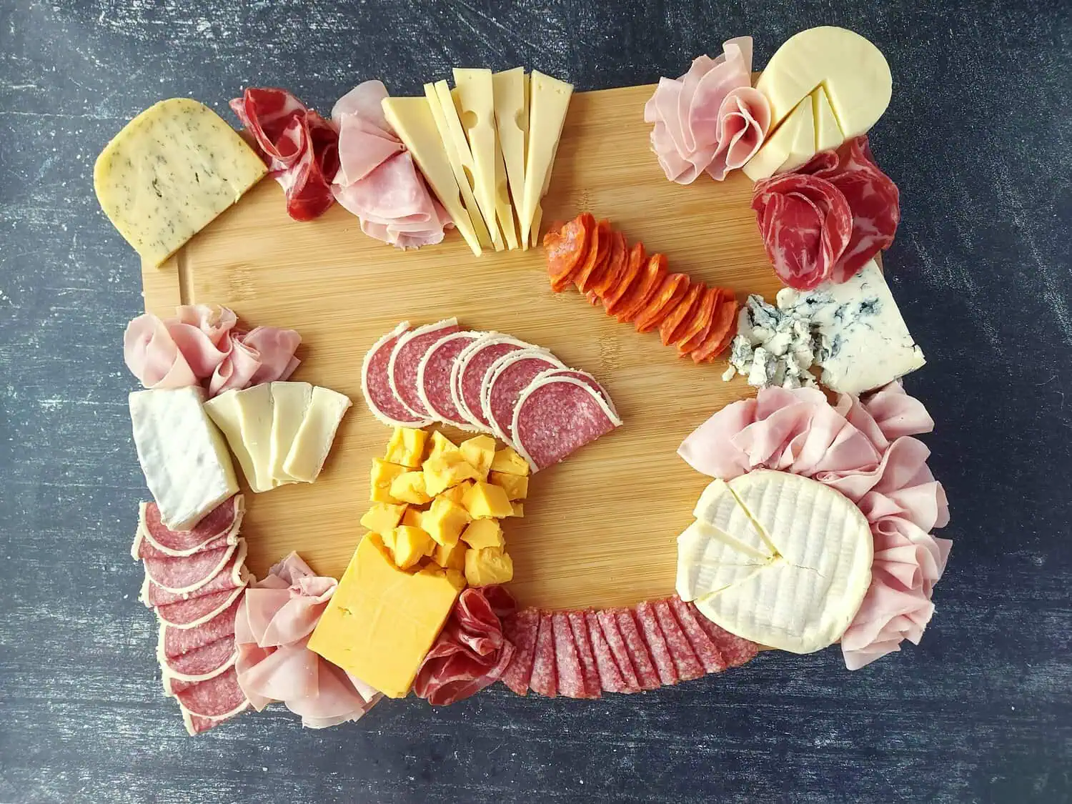 various cheeses and meats arranged on a charcuterie board