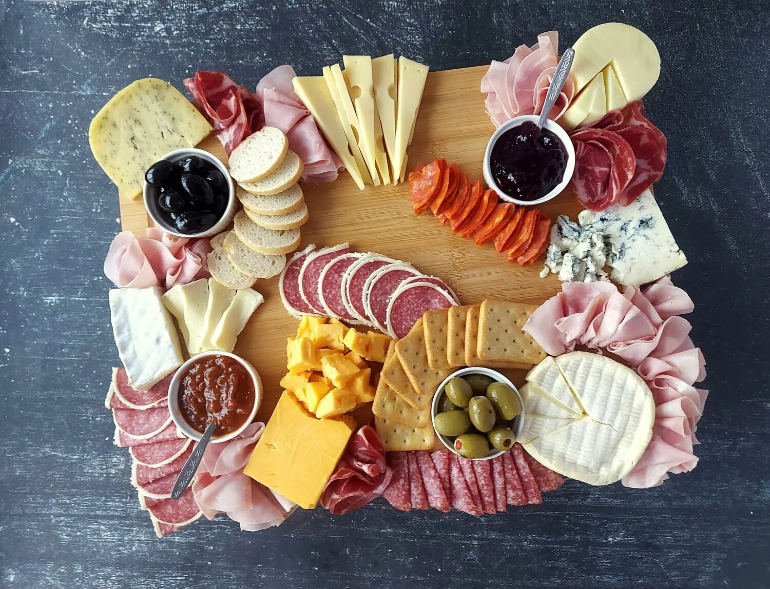 charcuterie board witn cheeses, meats, jams, olives, crackers and bread slices