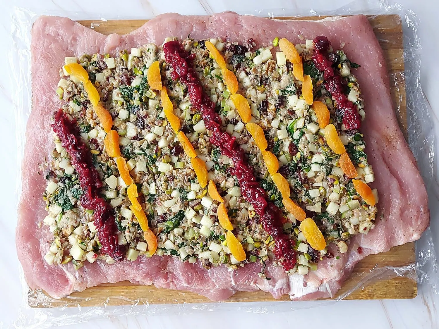 cranberry apple stuffed pork loin Butterflied pork loin roast covered with a layer of stuffing mix and diagonal lines of dried apricots and cranberry sauce