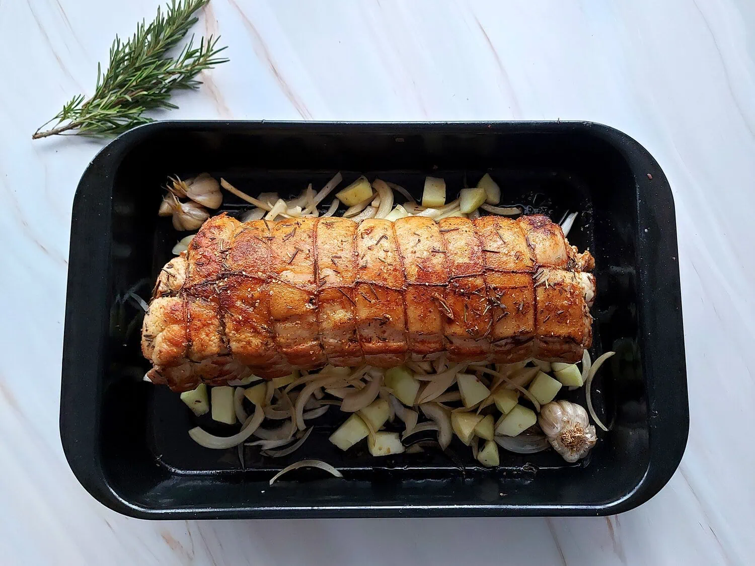 cranberry apple stuffed pork loin Golden brown pork loin roast on a bed of apples, onions and garlic in a baking sheet