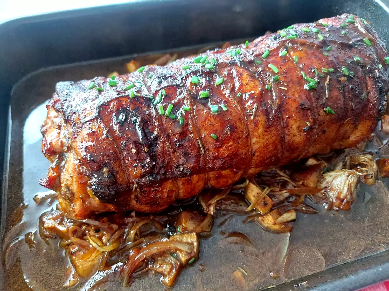 cranberry apple stuffed pork loin Roasted pork loin roulade on a bed of onions and apples in a pan