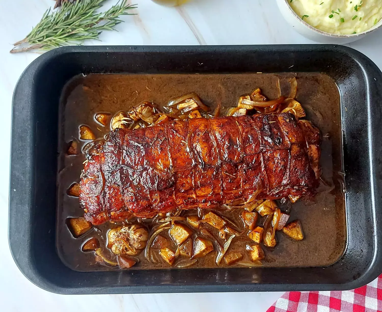 cranberry apple stuffed pork loin Whole apple cranberry pork loin in a pan, on a bed of apples and onions with cider sauce