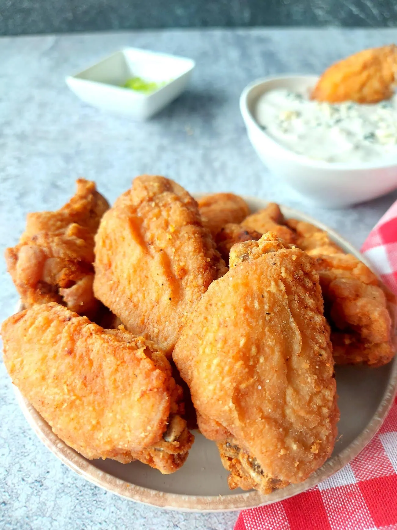 crispy fried chicken wings recipe Close up of a plate of crunchy fried wings with blue cheese sauce and chopped green onions in the background