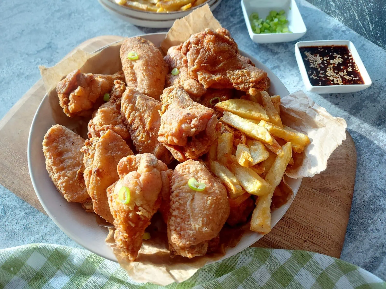 crispy fried chicken wings recipe A plate of fried drumettes and flats, with a soy dressing and chopped green onions in the background