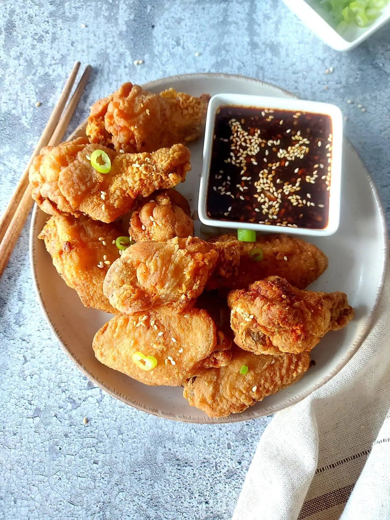 crispy fried chicken wings recipe Crispy chicken wings on a plate with soy sauce dipping with sesame seeds, and two chopsticks