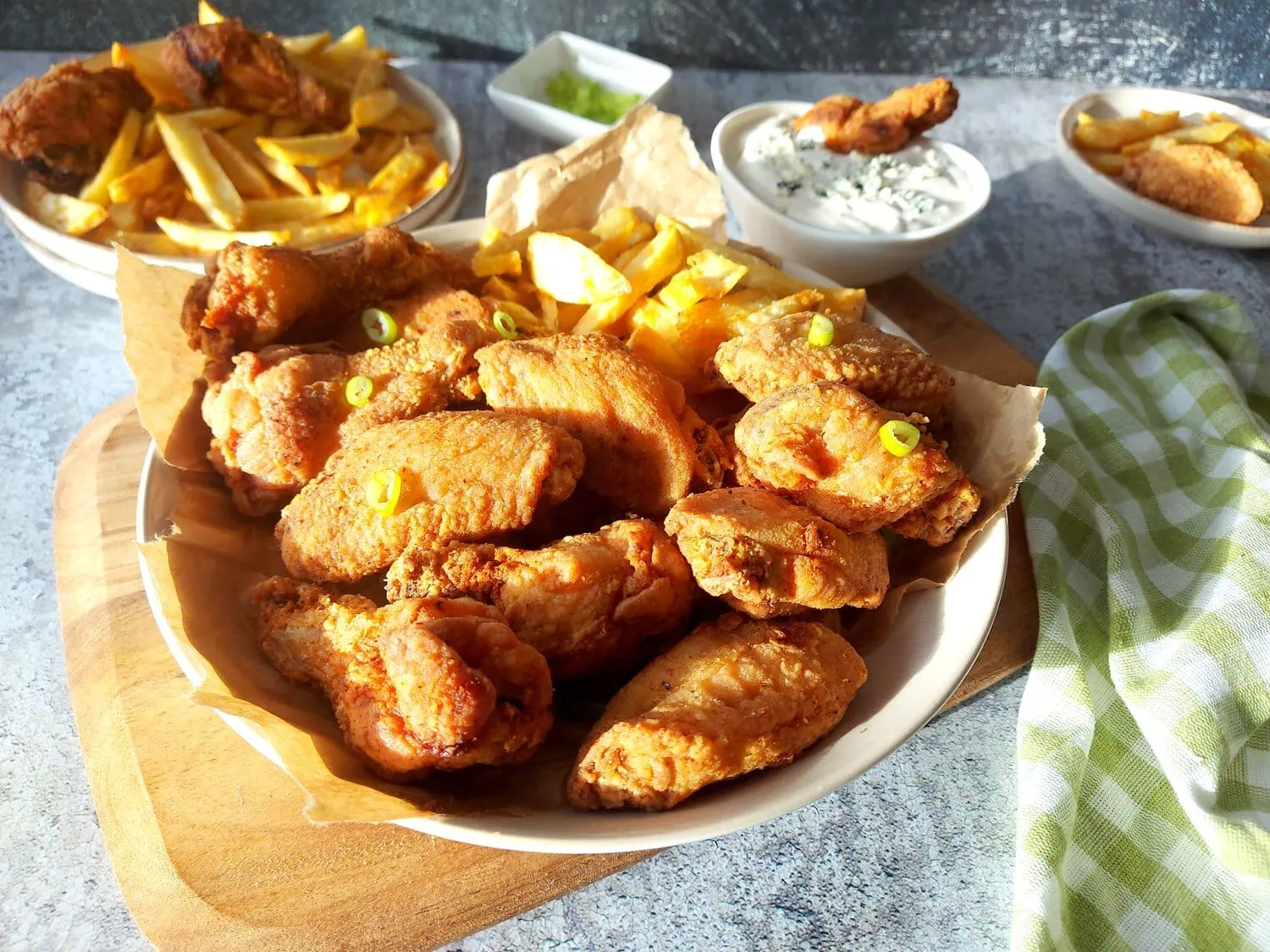 crispy fried chicken wings recipe A plate with fried wings and French fries, with blue cheese dip, and a plate of French fries in the background