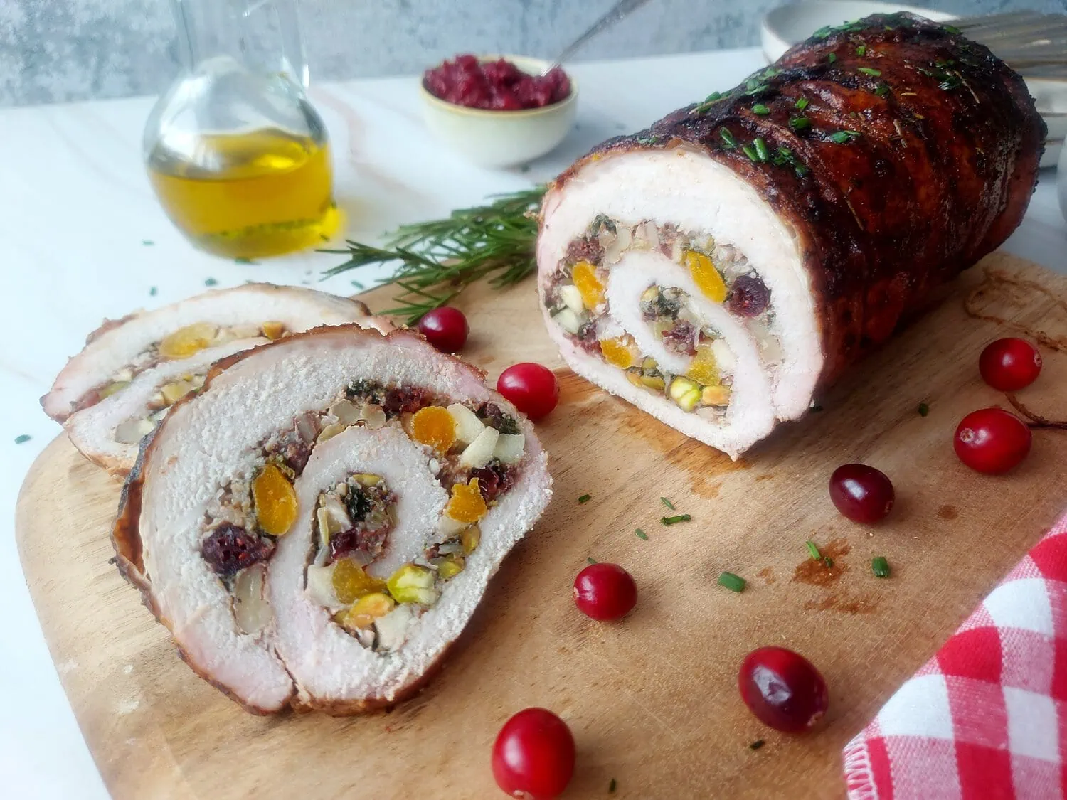 cranberry apple stuffed pork loin Eye level shot of a stuffed apple roast next to a slice of pork loin on a board with cranberries and a red and white napkin