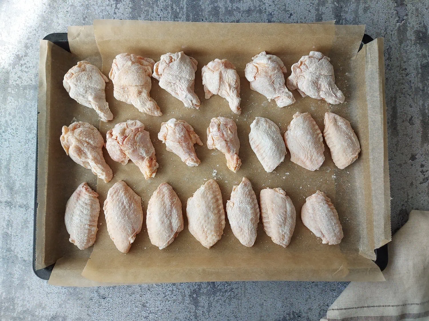 crispy fried chicken wings recipe chicken wings coated in the flour mixture, arranged on top of a baking sheet lined with baking paper