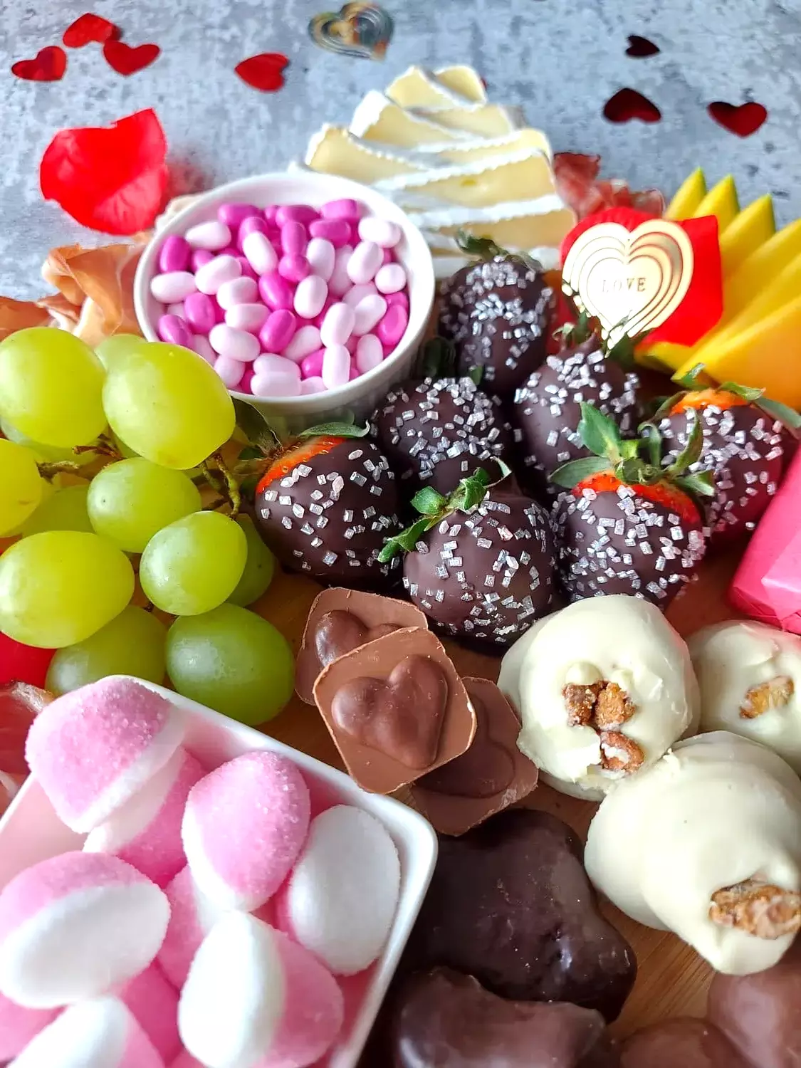 valentine's day charcuterie Close up of a Charcuterie board for two with chocolate covered strawberries, grapes, heart shaped chocolate and pink marshmallows