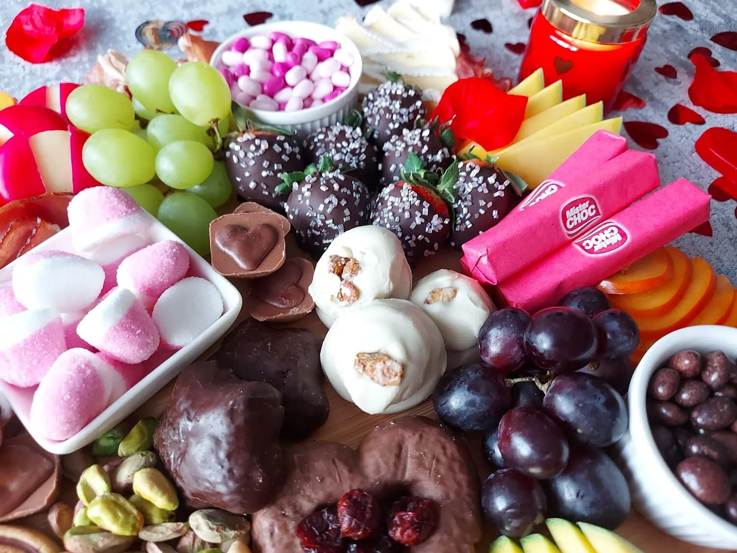 valentine's day charcuterie Close up of chocolate-covered strawberries, pistachio biscuits, pink marshmallows, chocolate-covered raisins, dried cranberries and mango slices