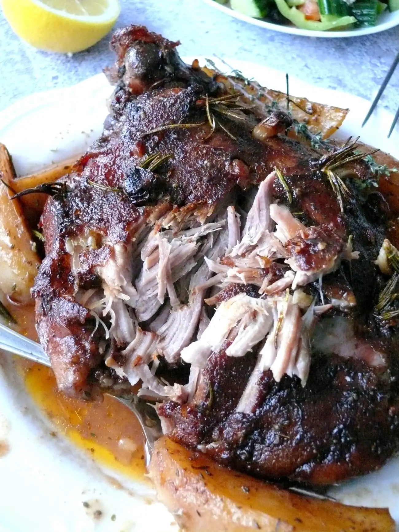 Close-up of shredded piece of lamb on a plate with gravy and potatoes