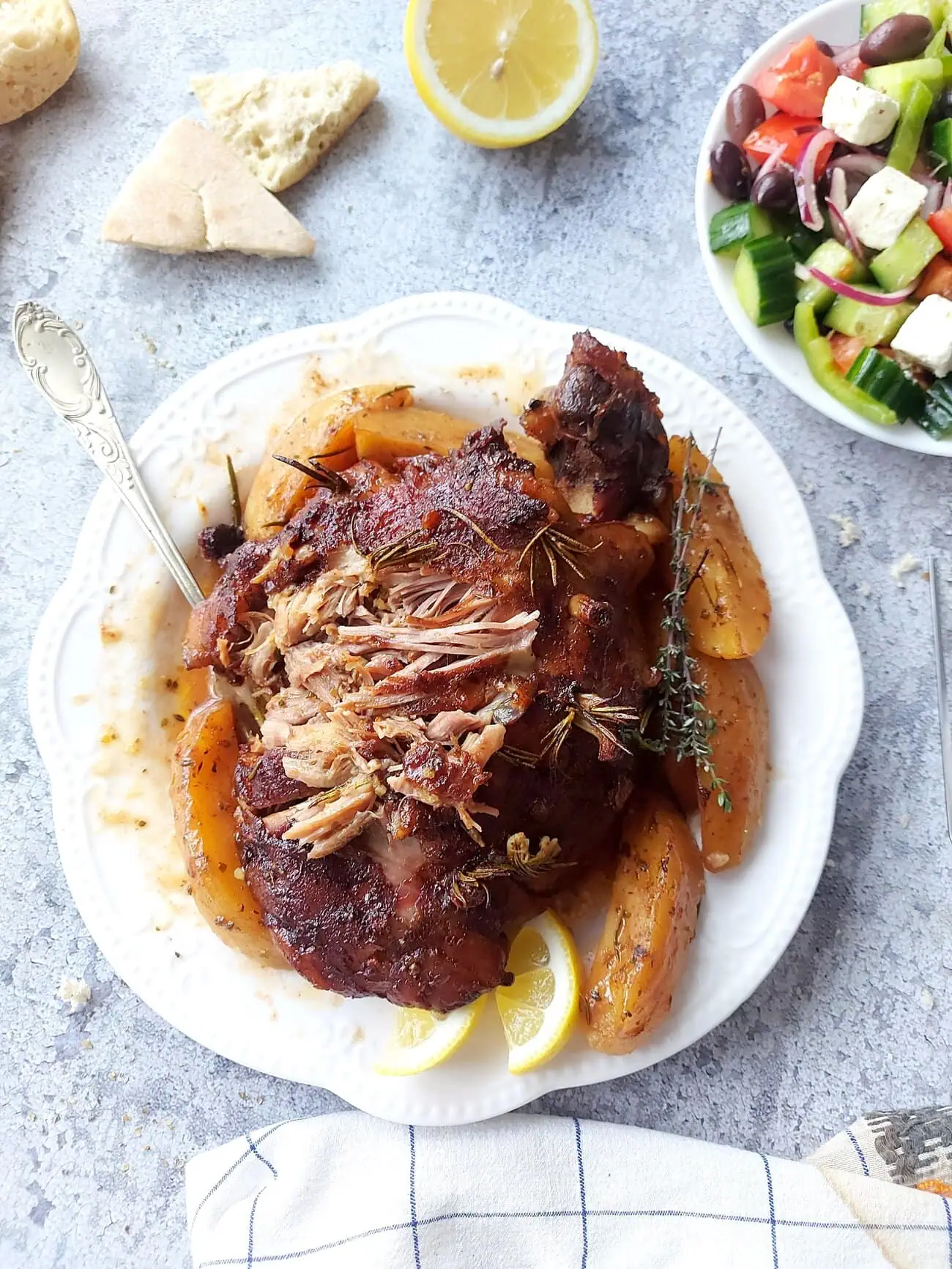 Overhead shot of a plate with shredded lamb meat with potatoes, gravy and lemon wedges