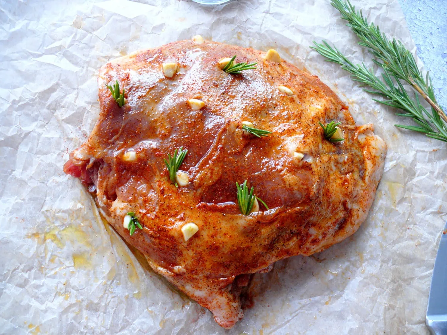 raw leg of lamb with garlic slivers and rosemary sprigs tucked into incisions 