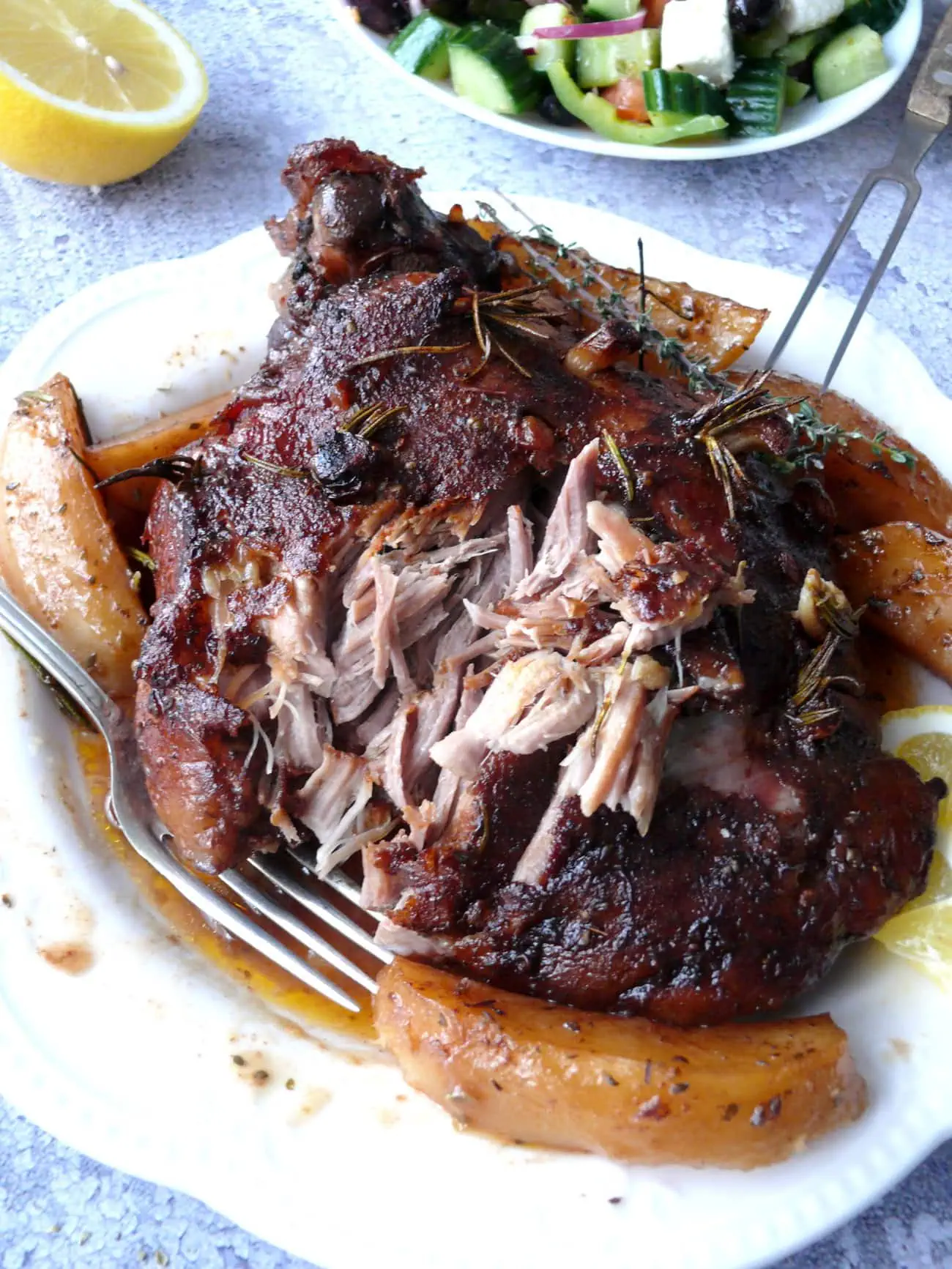 Closeup of shredded tender roast leg of lamb on a white plate