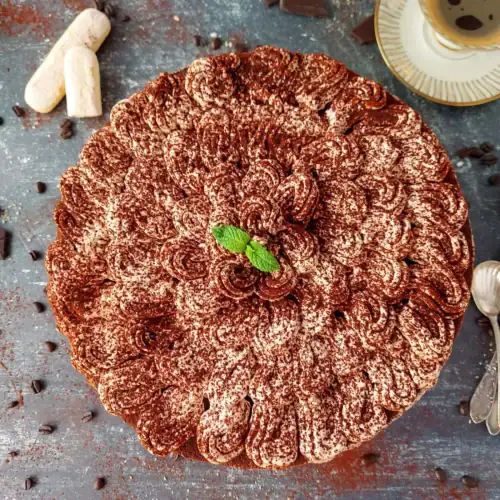 close up image of a slice of tiramisu cheesecake with a fork on a plate