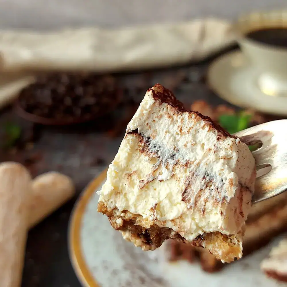 close up shot of a bite of a cheesecake tiramisu on a fork