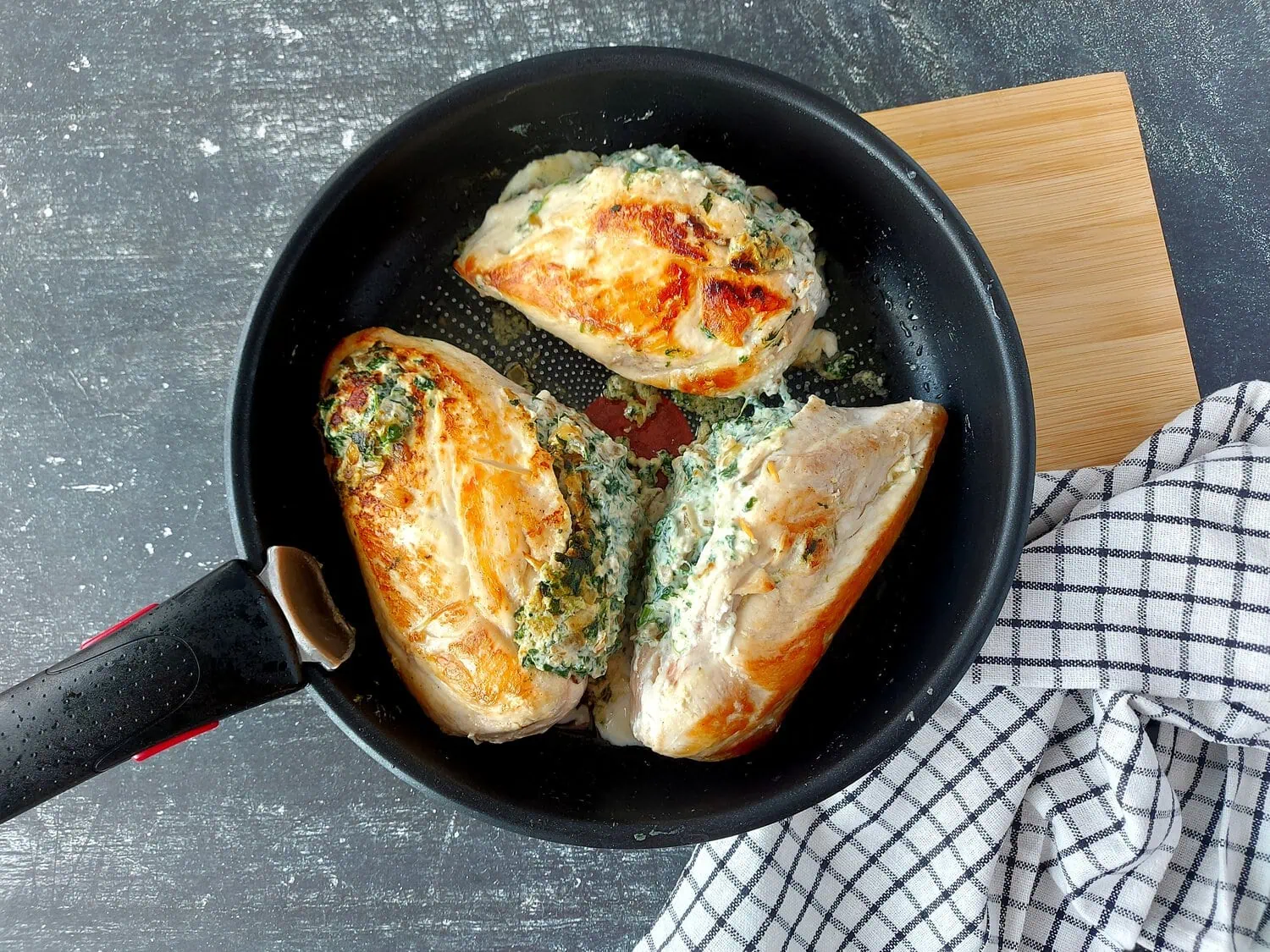 threes chicken breasts stuffed with the ricotta mixture in a black skillet
