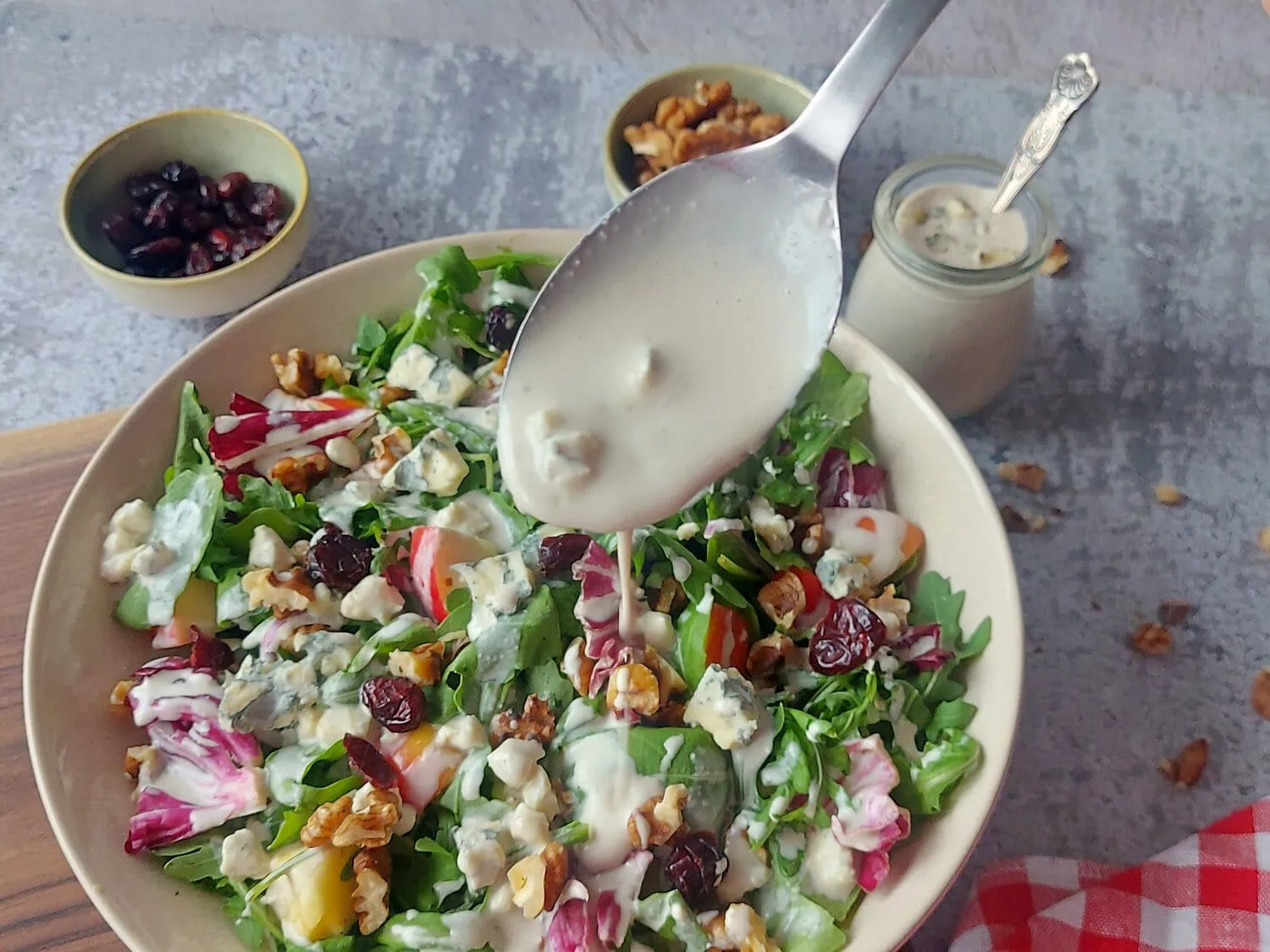 apple walnut blue cheese salad dressing drizzled over a bowl of mixed salad greens