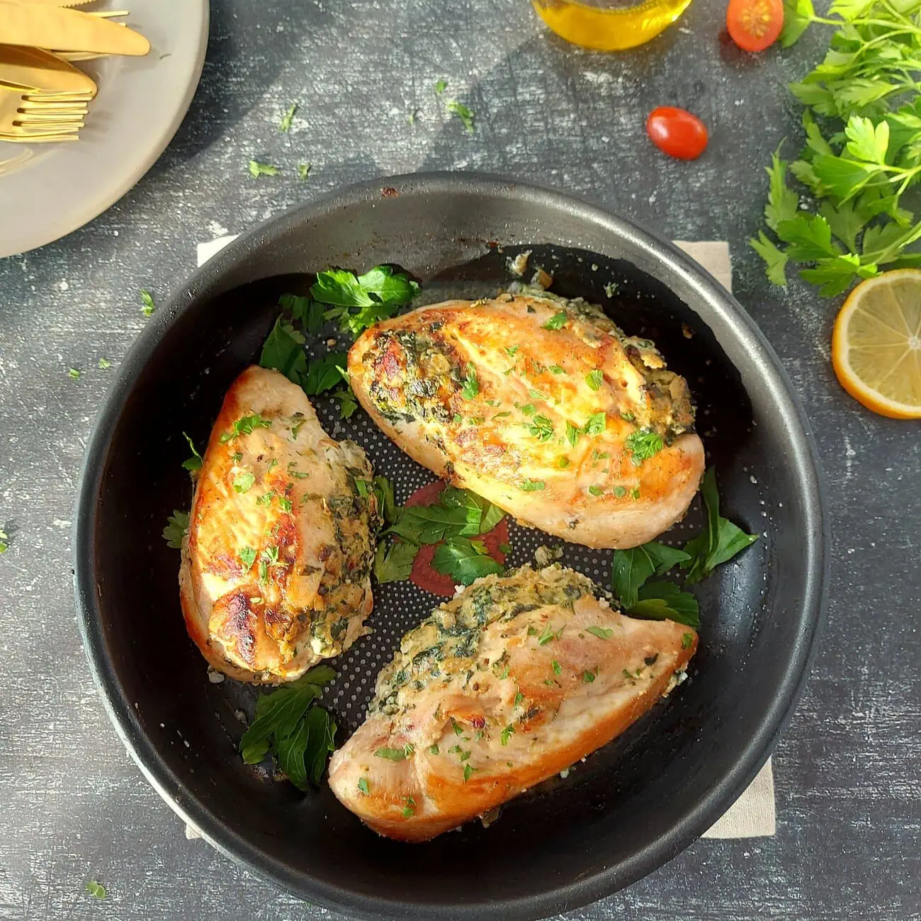 overhead shot of a skillet with three chicken breasts sprinkled with parsley