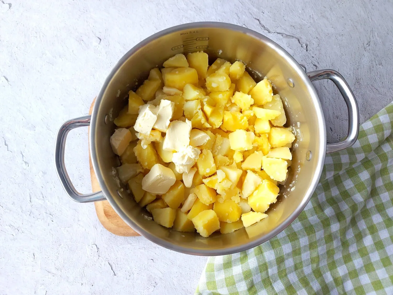 Boiled potatoes topped with butter in a large pot 
