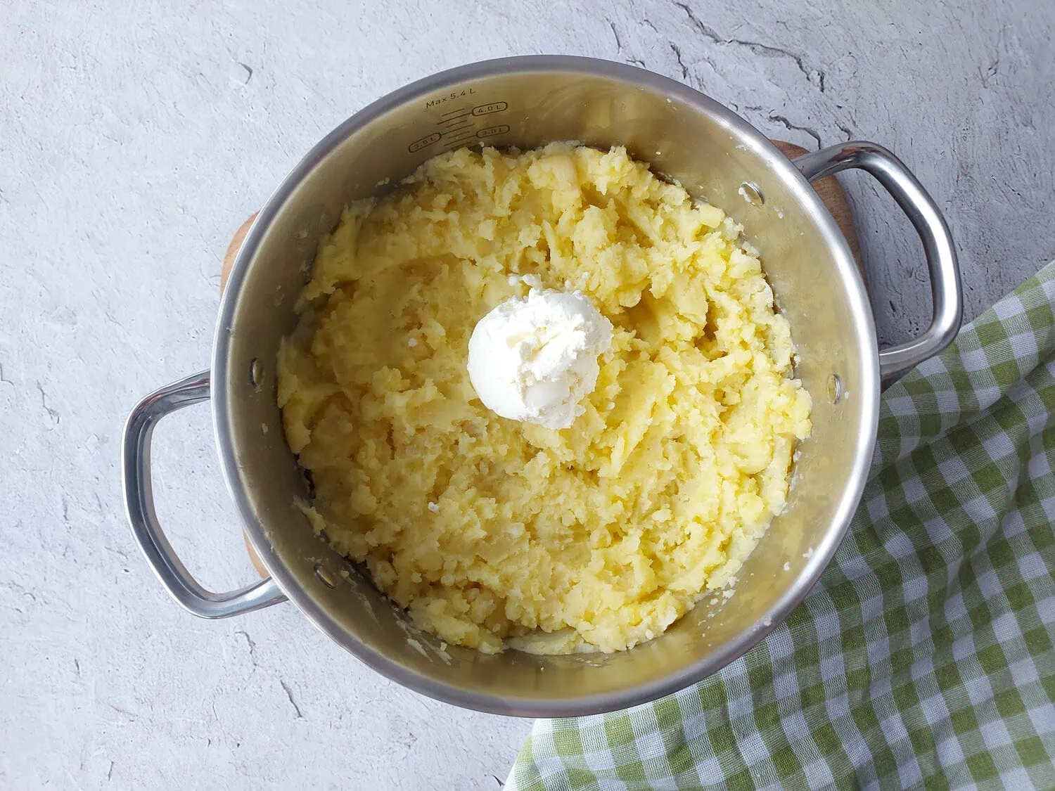 Mashed potatoes topped with cream cheese in a large popt