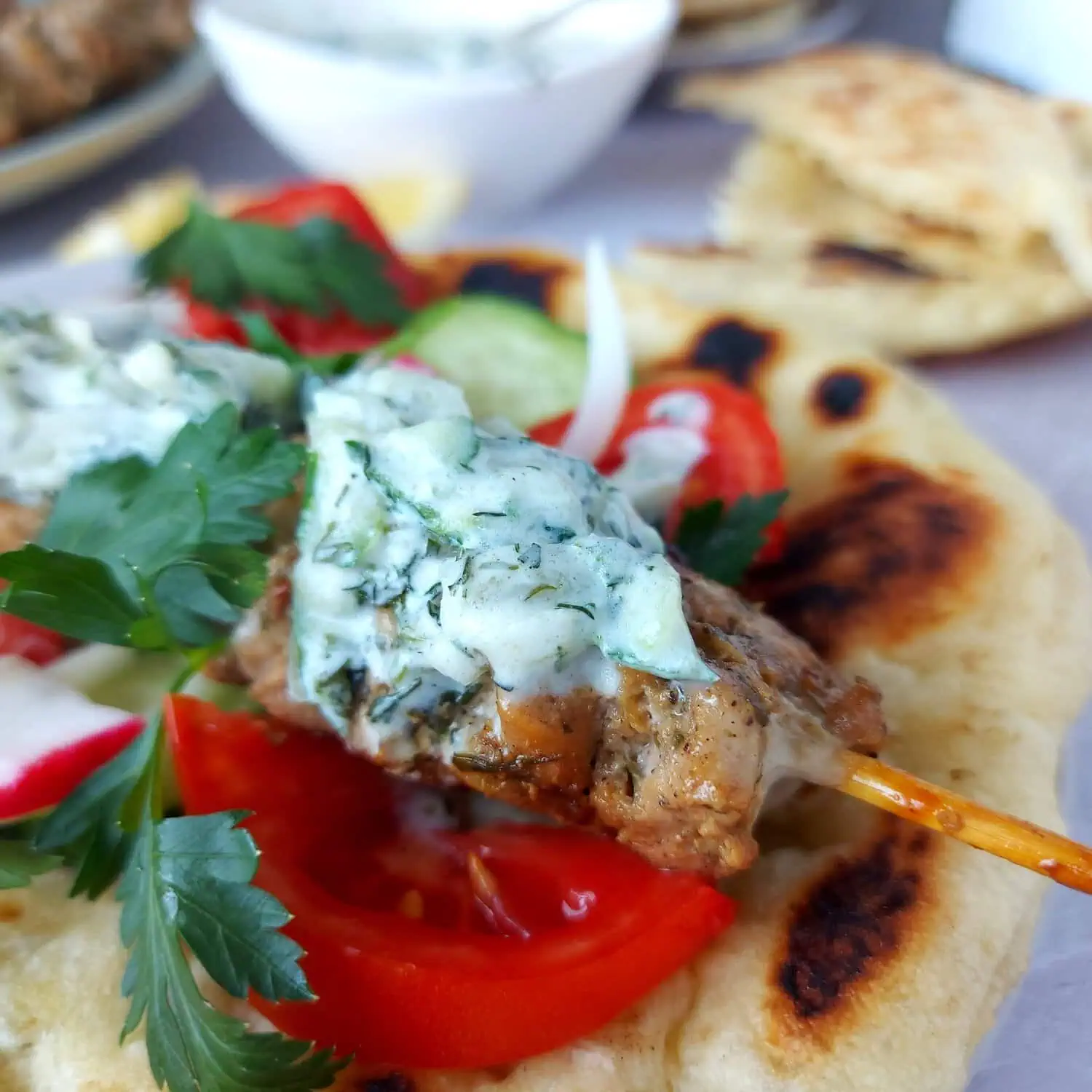 traditional greek souvlaki Close-up shot of a souvlaki skewer drizzled with tzatziki sauce on a piece of pita bread