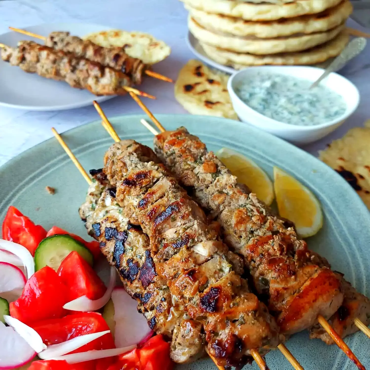 traditional greek souvlaki souvlaki chicken skewers on a plate with a tomato, onion, and cucumber salad on the side