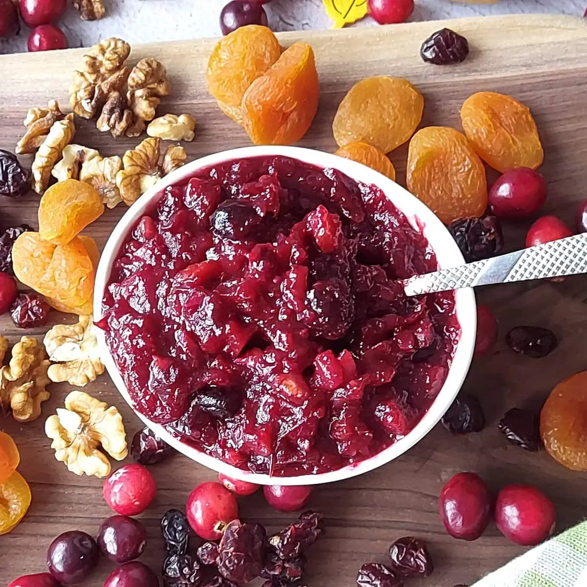 homemade cranberry sauce with orange juice Cranberry and orange juice sauce in a ramekin surrounded by dried apricots, walnuts, fresh and dried cranberries
