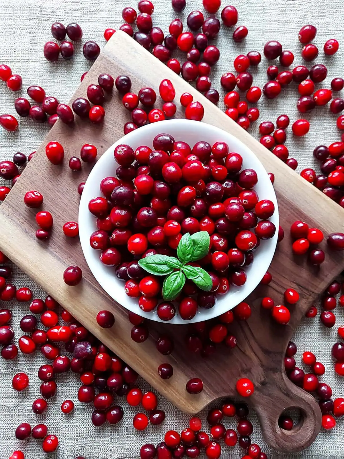 homemade cranberry sauce with orange juice Fresh cranberries in a white bowl surrounded by fresh cranberries on a table